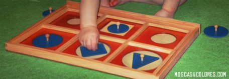 Bebé jugando a encajar piezas en un tablero sin seguir las formas (normas).