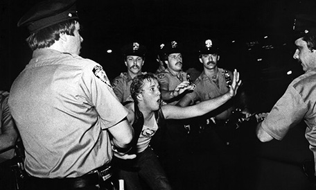 Fotografía en blanco y negro de un chico enfrentándose a la policía.