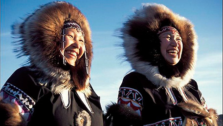 Dos mujeres Inuit sonriendo, ataviadas con sus abrigos típicos,