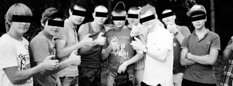 El comando Okkupay Pedofilyay Miembros de Okkupay Pedofilyay, con su característico signo realizado con la mano, el signo OK pero doblando el pulgar. Foto en blanco y negro con una franja negra añadida tapando los ojos.